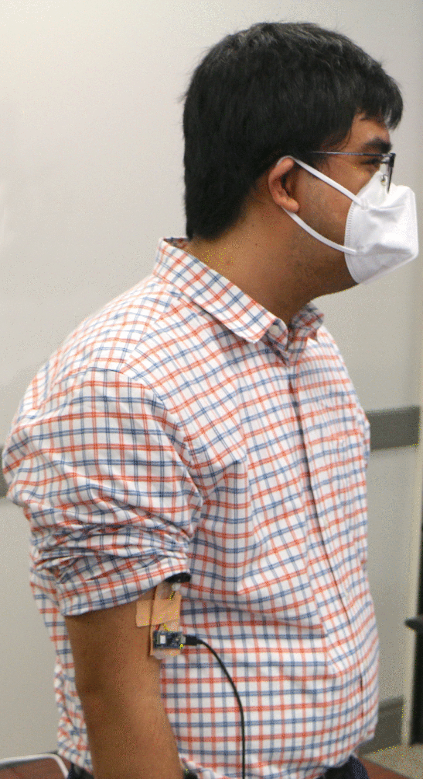 Photograph of Reiner wearing a mask and demonstrating a stick-and-peel prototype project on his right arm